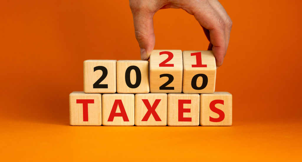 Business concept of planning 2021. Male hand flips wooden cubes and changes the inscription 'Taxes 2020' to 'Taxes 2021